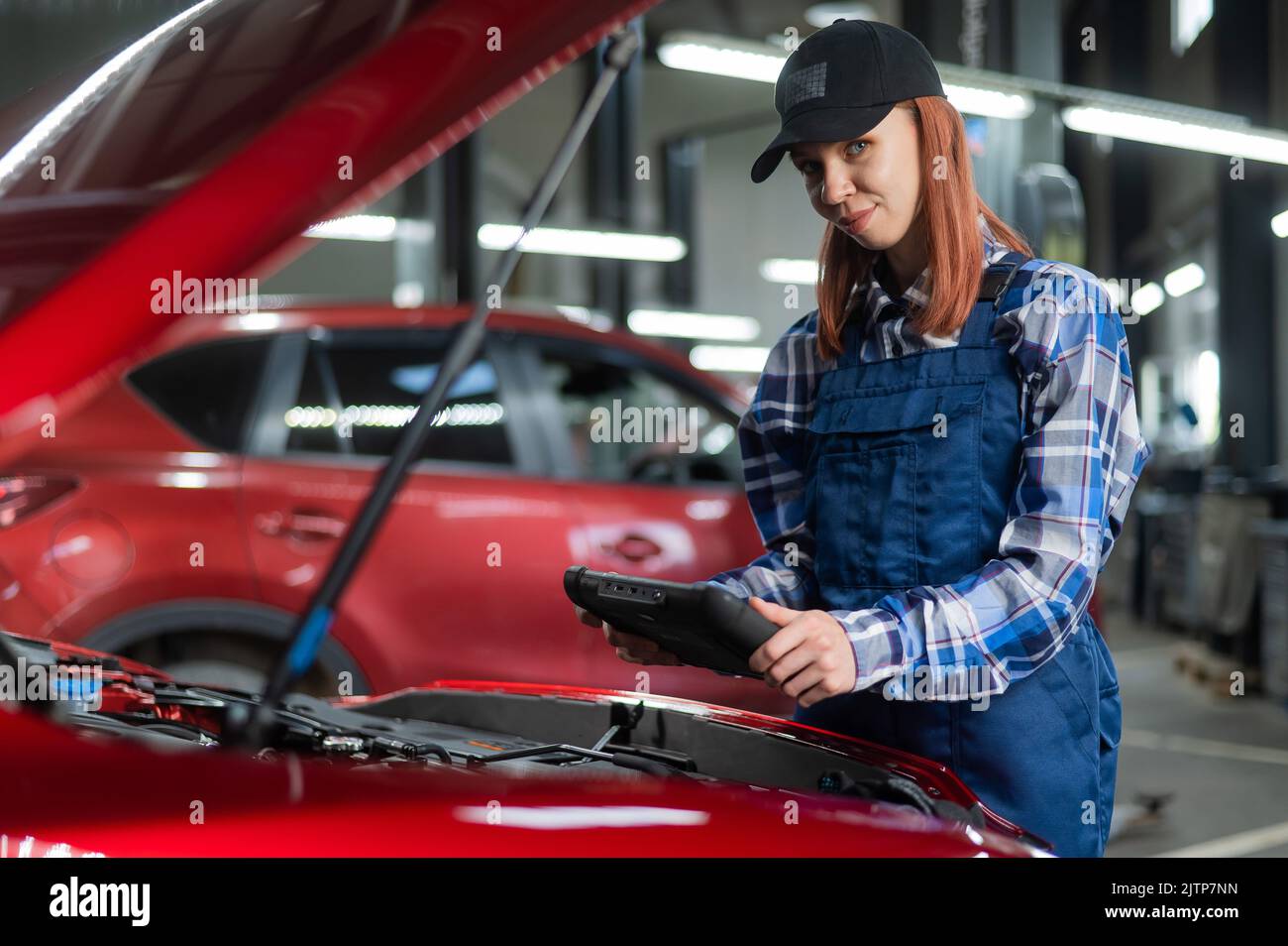 Caucasian female auto mechanic uses a special computer to diagnose