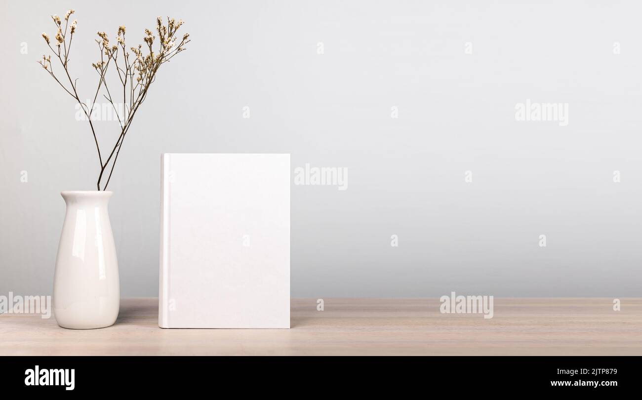 Banner with book mockup and dried flowers in vase at wooden table