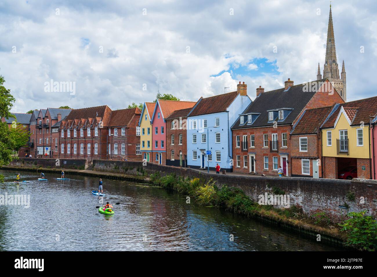 Colourful houses on Quayside in Norwich, North Norfolk, UK along the River Wensum with paddleboarders sailing passed Stock Photo