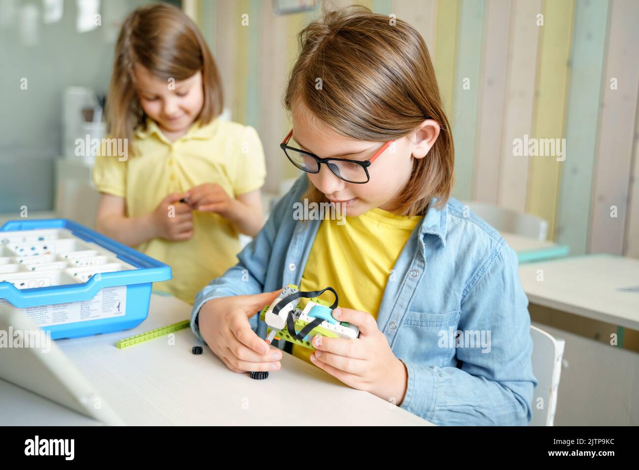 Programming work, learning robotics in elementary school. Children students assembly, launch, coding of robot. Constructor parts by instructions in ta Stock Photo