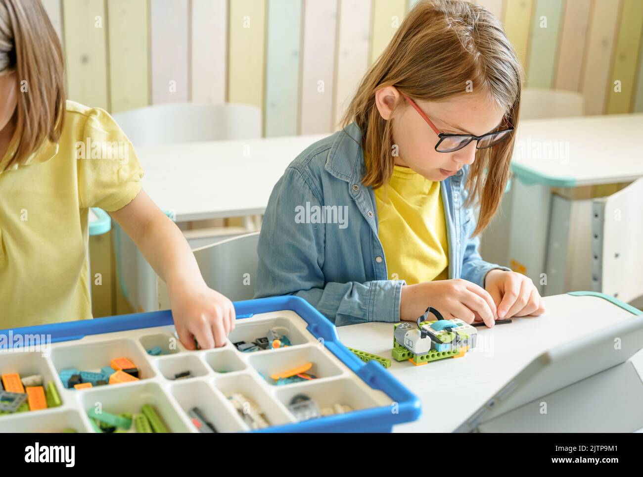 Programming work, learning robotics in elementary school. Children students assembly, launch, coding of robot. Constructor parts by instructions in ta Stock Photo