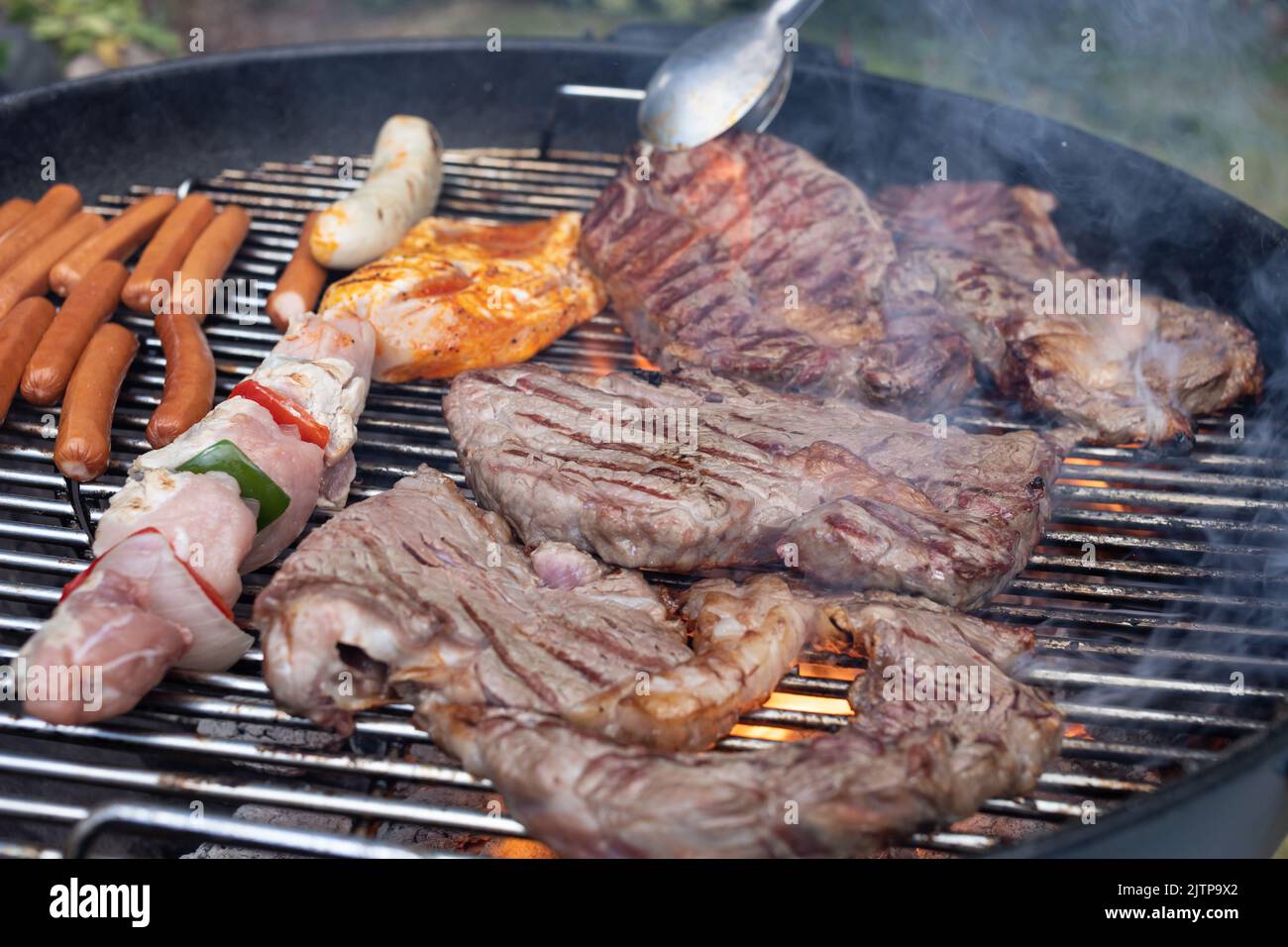 large beef steaks and sausages on charcoal grill Stock Photo
