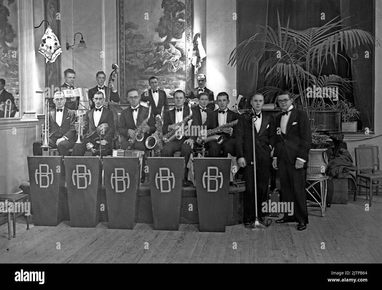 A British dance band, The Harry Blake Orchestra, at the Portman Rooms, Baker Street, London, UK in November 1937. With 12 members, this was a sizable band and, unusually for the time, included a bass player and guitarist. Blake is photographed on the right. Early dance and swing bands had their heyday in the UK during the 1920s–30s. Bands played in dance halls and hotel ballrooms. They played melodic, good-time music and individual players would play in several bands. This image is from an old glass negative – a vintage 1930s photograph. Stock Photo