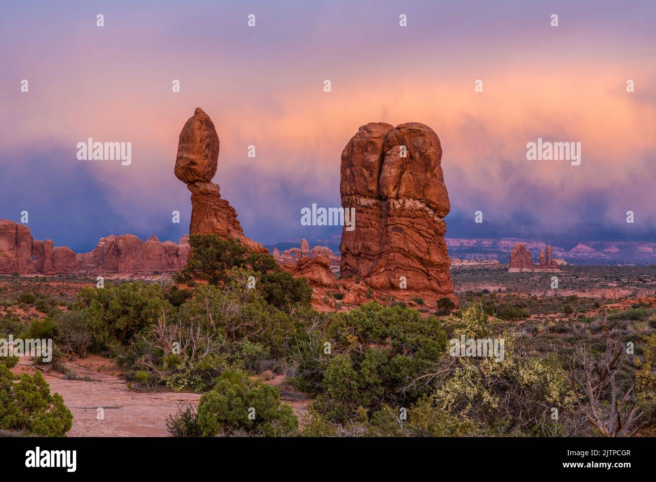 Colorful storm clouds in post-sunset light over Balanced Rock in Arches National Park, Moab, Utah. Stock Photo