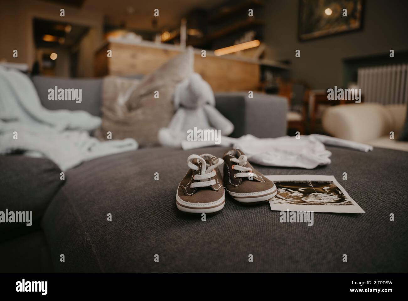 Mother to be places baby's ultrasound and shoes on the sofa  Stock Photo
