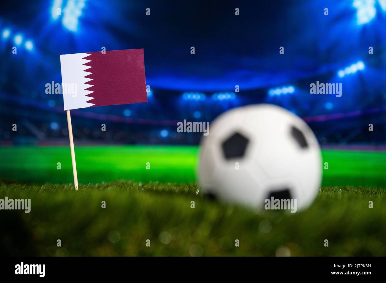 Qatar Flag on Green Grass of Modern Football Stadium in Night. Sport photo, Dark edit space Stock Photo