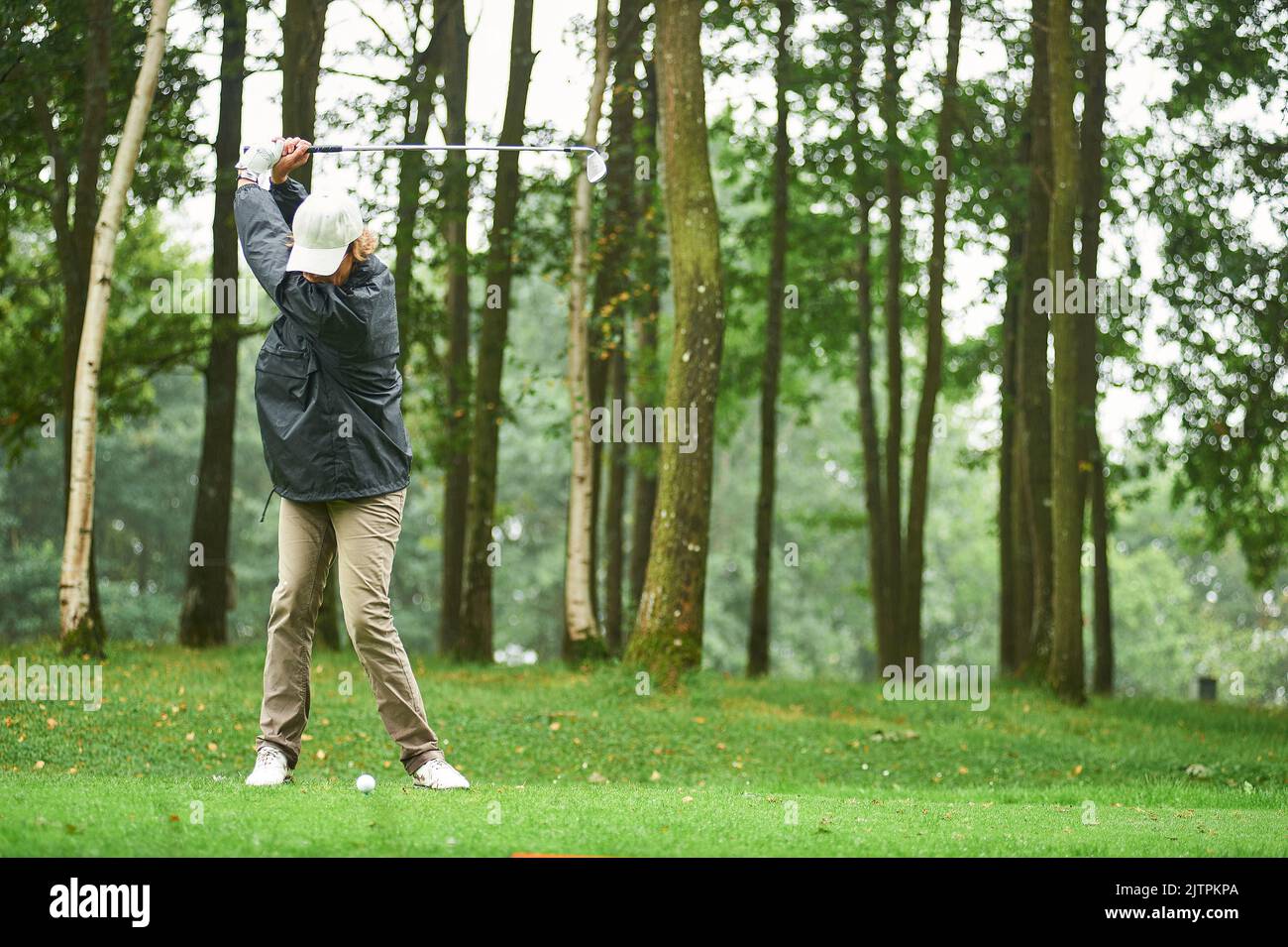 woman with cap playing golf under rain Stock Photo