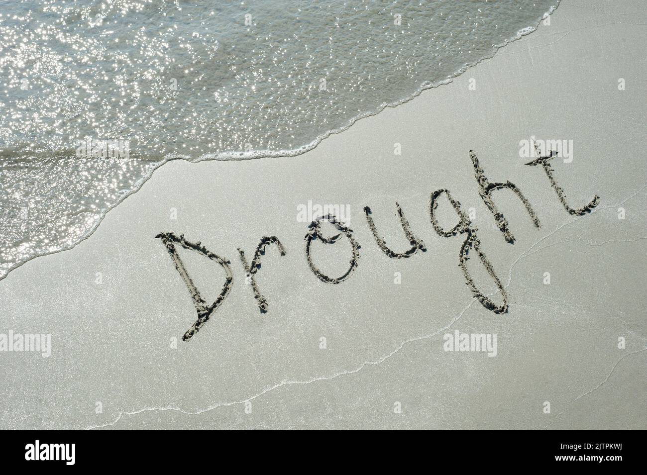 Concept or conceptual Drought handwritten text in sand on a beach with ...
