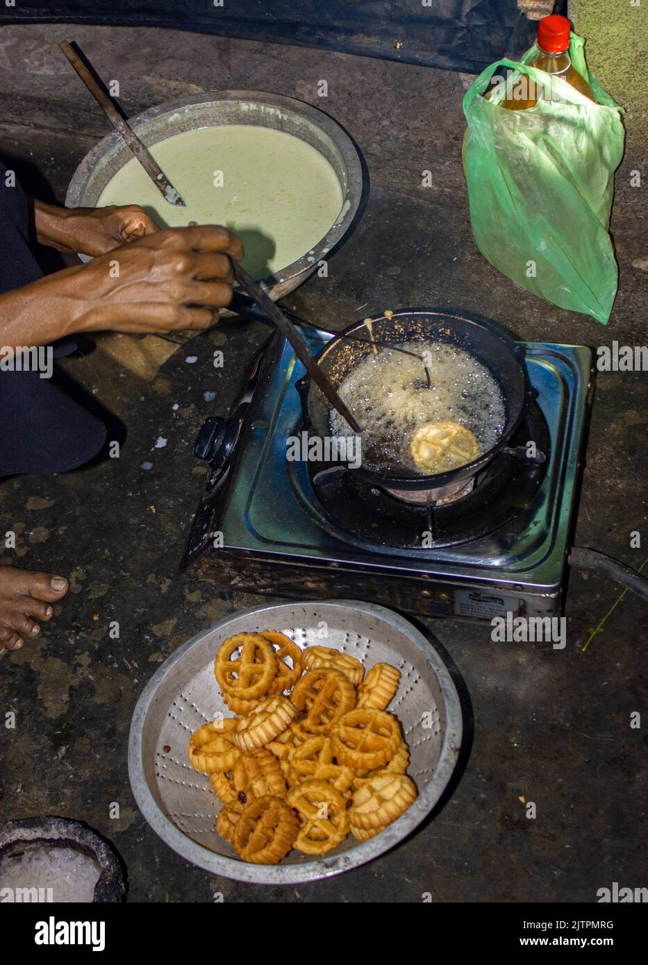 Village cooking; village girl cooking; frying sweets; traditional food; frying kokis; making cookies; rosette cookies; frying rosette cookies; dutch c Stock Photo