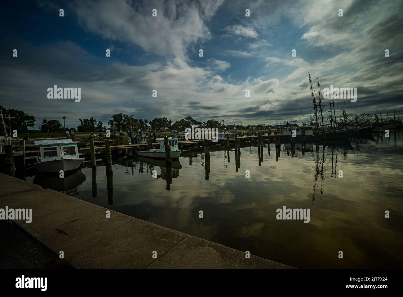 The view of docked boats under the cloudy sky reflecting on the water ...