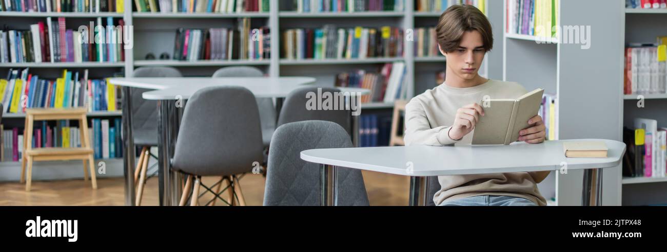 teenage boy sitting in library reading room with book, banner,stock image Stock Photo