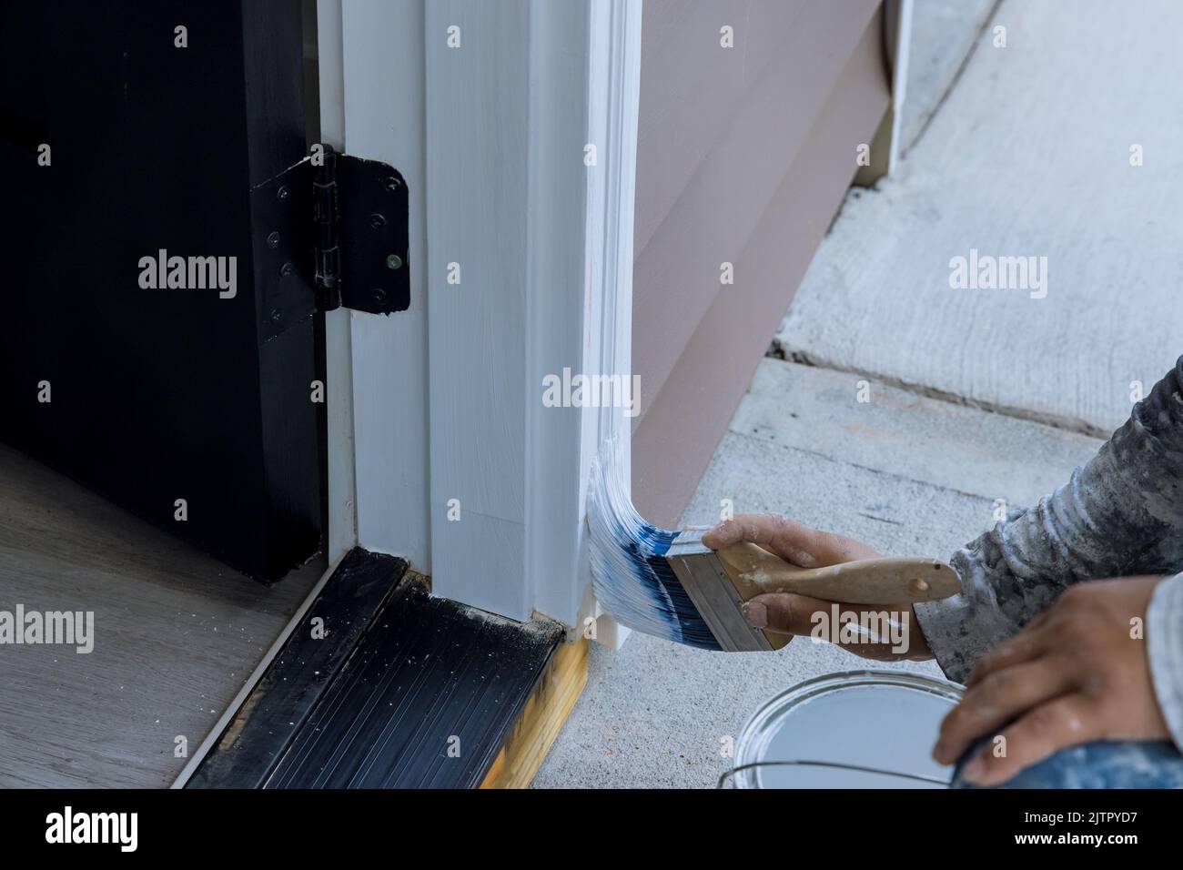 Using a paintbrush and a wooden molding, a carpenter works on painting