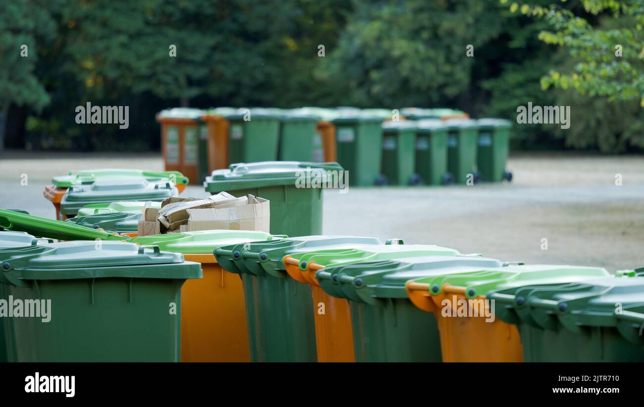 Cluster of green and orange plastic trash bin containers for paper