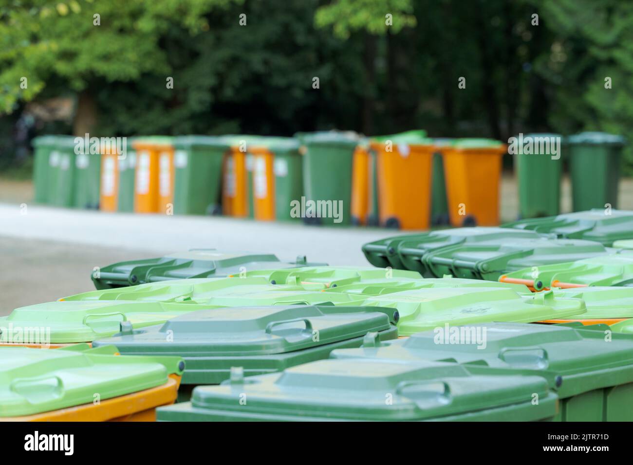 Cluster of green and orange plastic trash bin containers for paper