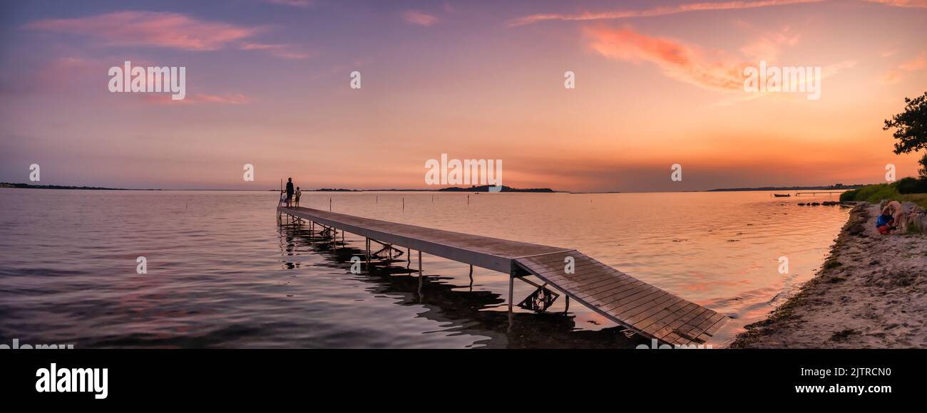 Sunset with children playing on a pier at Faldsled campin on Funen in Denmark Stock Photo