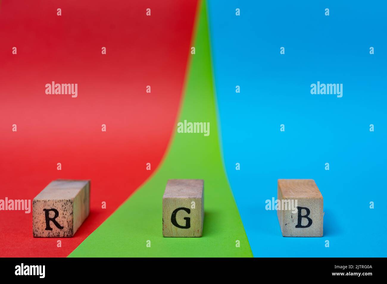 RGB color space. The letters R G and B on a wooden towel on a red, green, and blue background Stock Photo