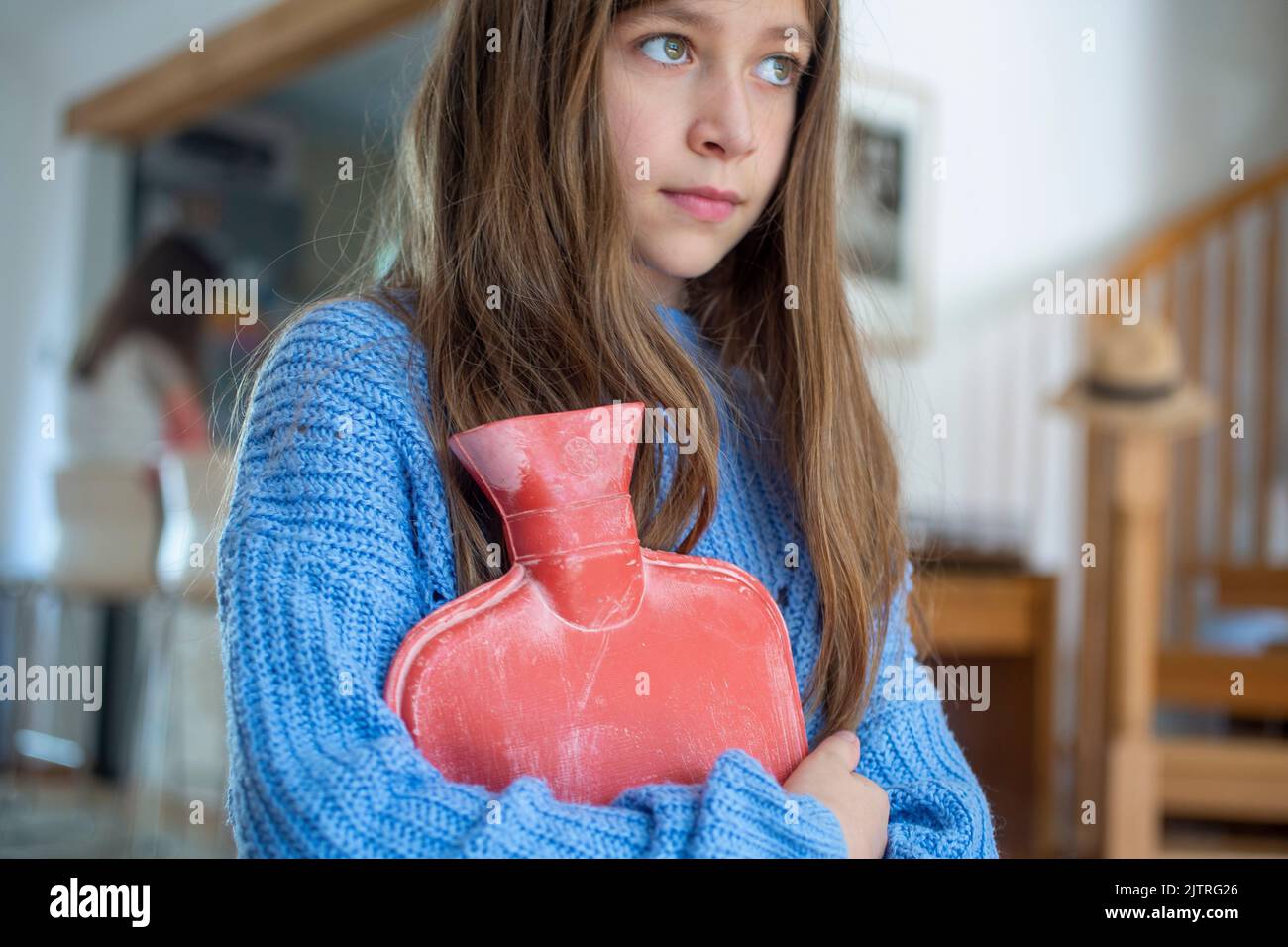 child holding a hot water bottle , trying to keep warm as fuel bills rocket Stock Photo