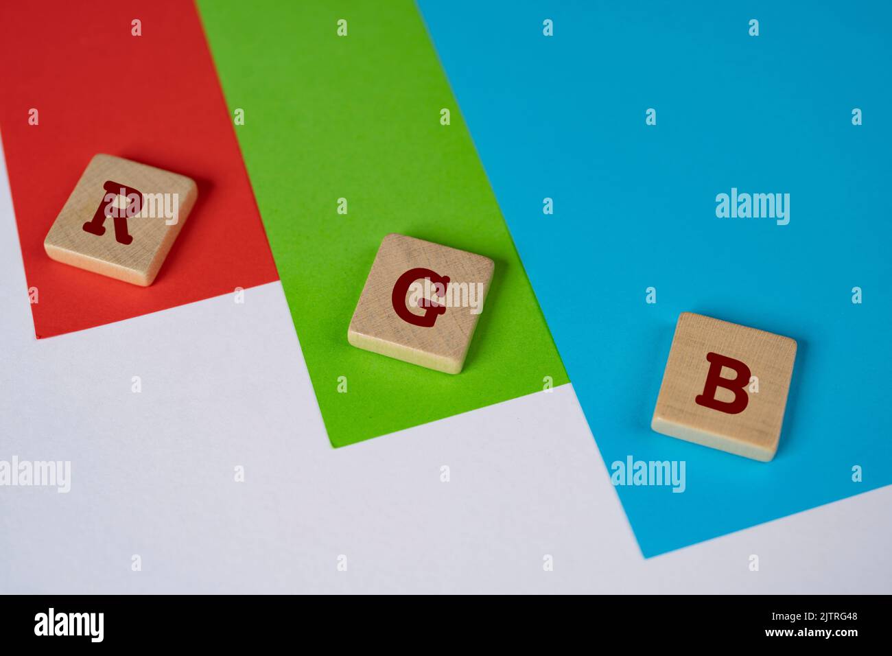 RGB color space. The letters R G and B on a wooden towel on a red, green, and blue background Stock Photo