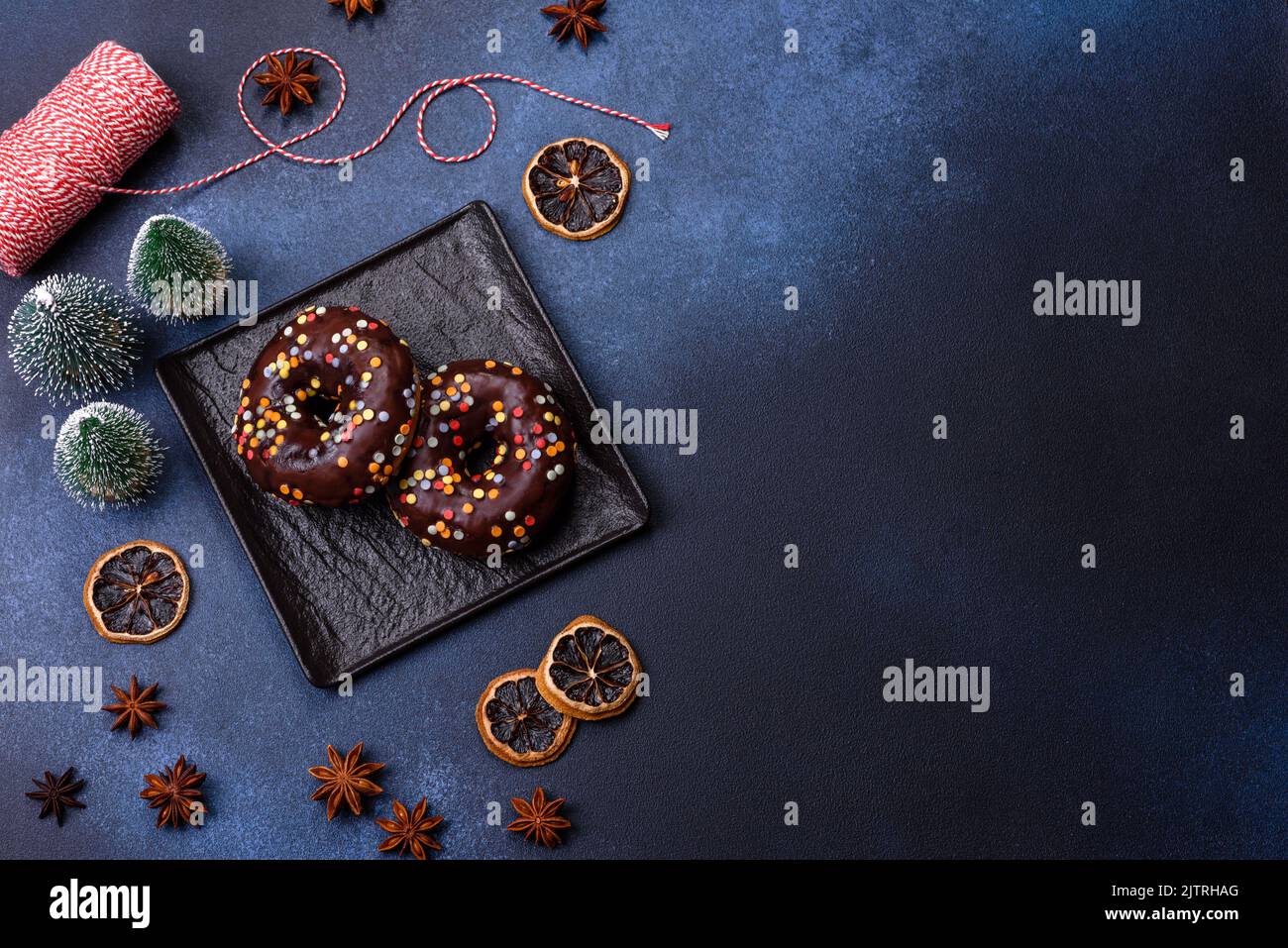 Pastries concept. Donuts with chocolate glaze with sprinkles, on a dark concrete table. Sweet food for a breakfast Stock Photo