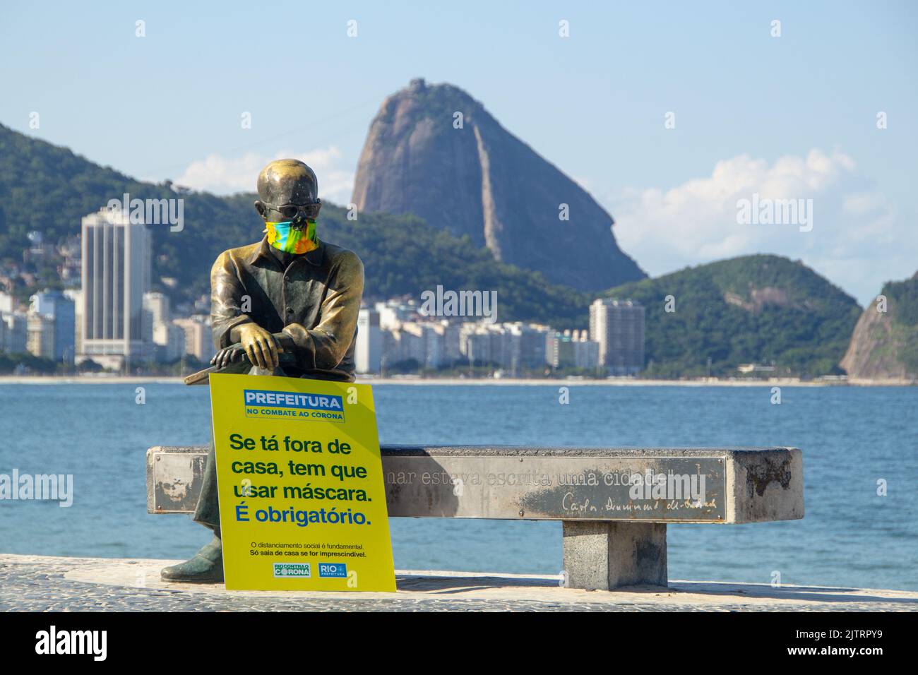 Statue of Carlos Drummond de Andrade with mask in Rio de Janeiro, Brazil - April 23, 2020: Statue with mask and information board written in Portugues Stock Photo