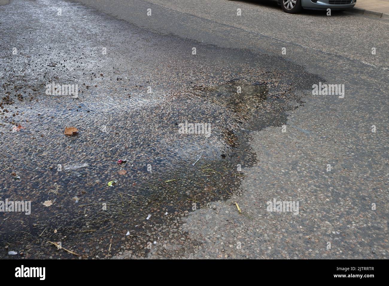 Water from an underground burst pipe escapes through the road surface