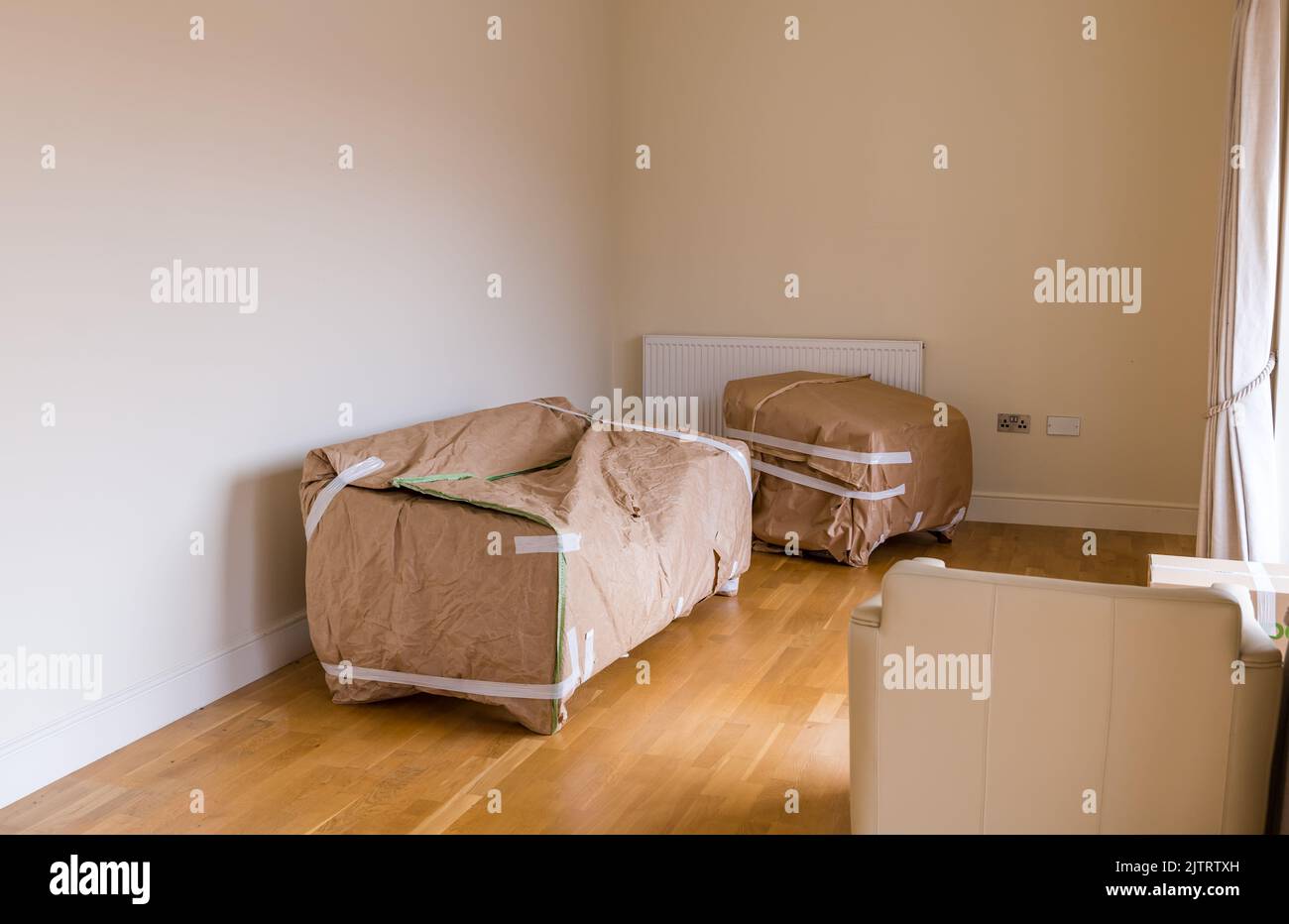 Packing and moving house with sofa and armchair furniture wrapped in sitting room packed ready for removals, Scotland, UK Stock Photo