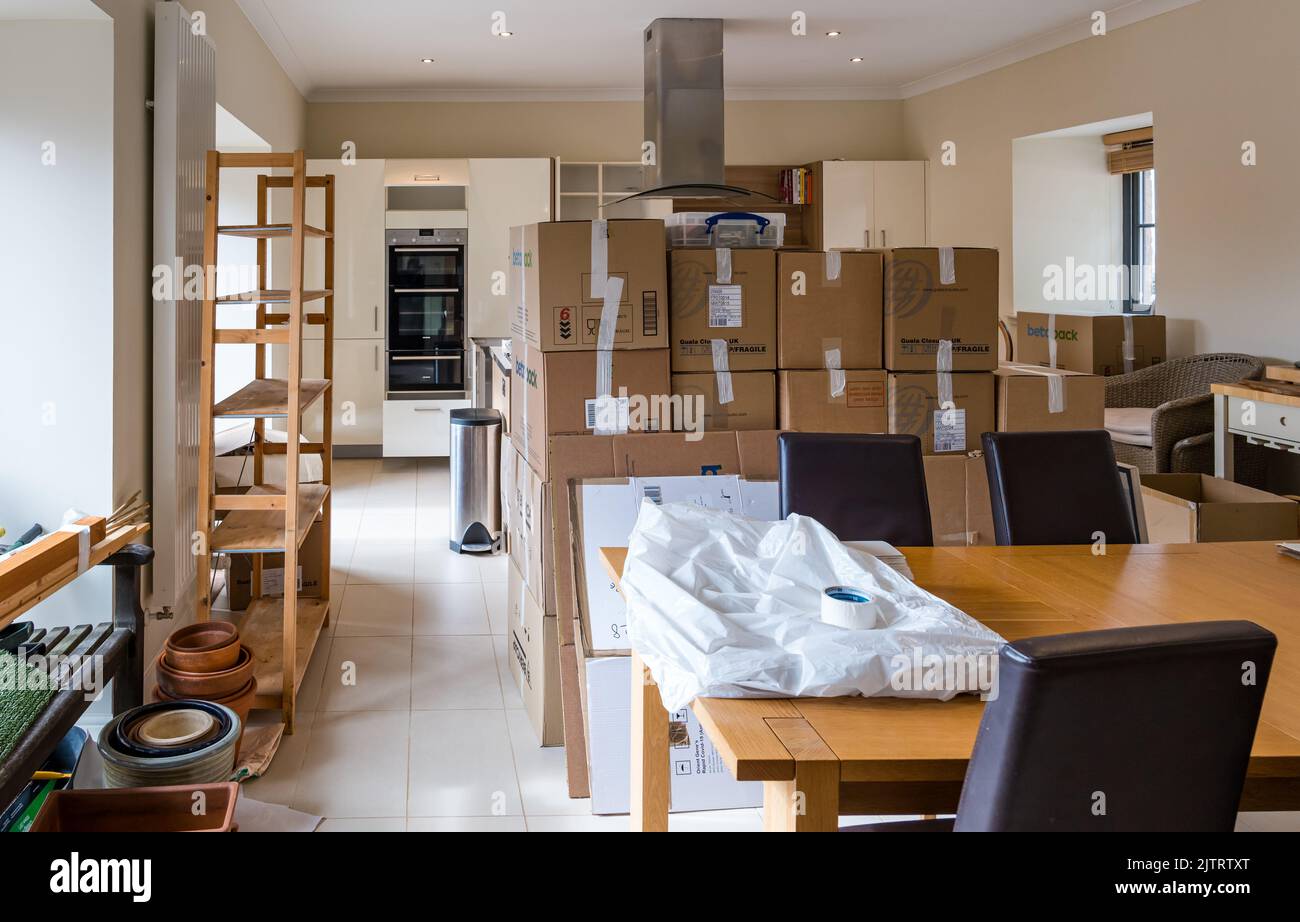 Packing and moving house with stack of boxes, furniture and household items in kitchen of house ready for removal, UK Stock Photo