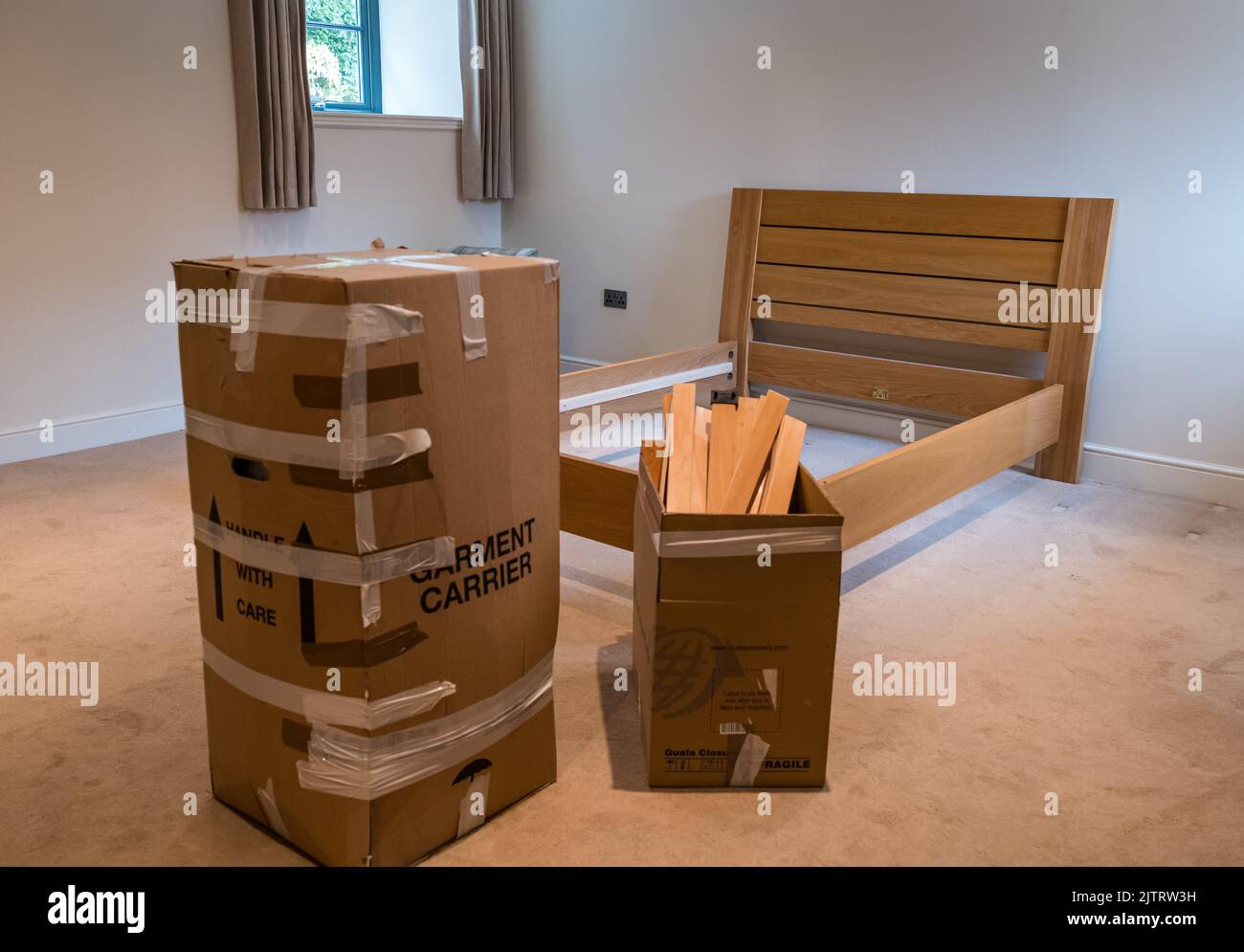 Packing and moving house with double bed dismantled for storage in bedroom and boxes packed ready for removals, Scotland, UK Stock Photo