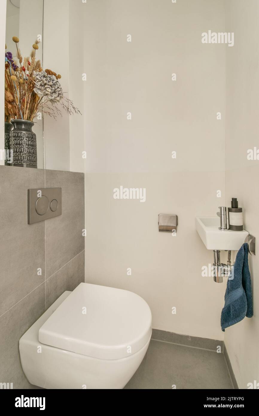 Wall hung toilet and small sink in corner in lavatory room Stock Photo
