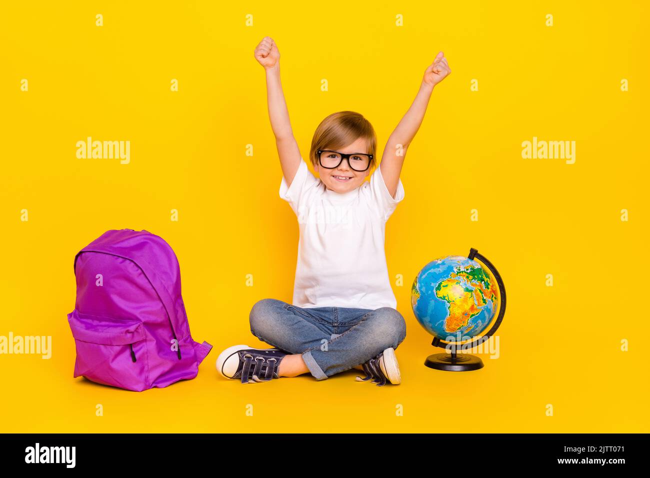 Portrait of handsome cheerful lucky pre-teen boy sitting rising hands ...