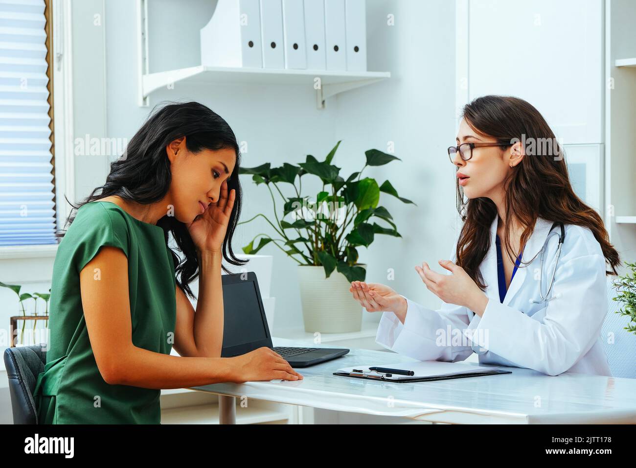 young female doctor explaining treatment to worried woman patient at health checkup Stock Photo