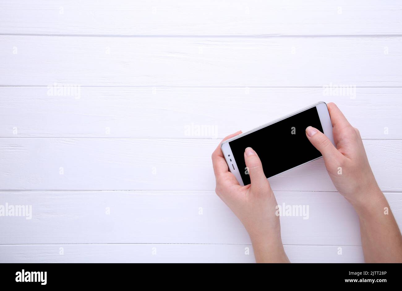 Female hands holding mobile phone with blank screen on white background ...