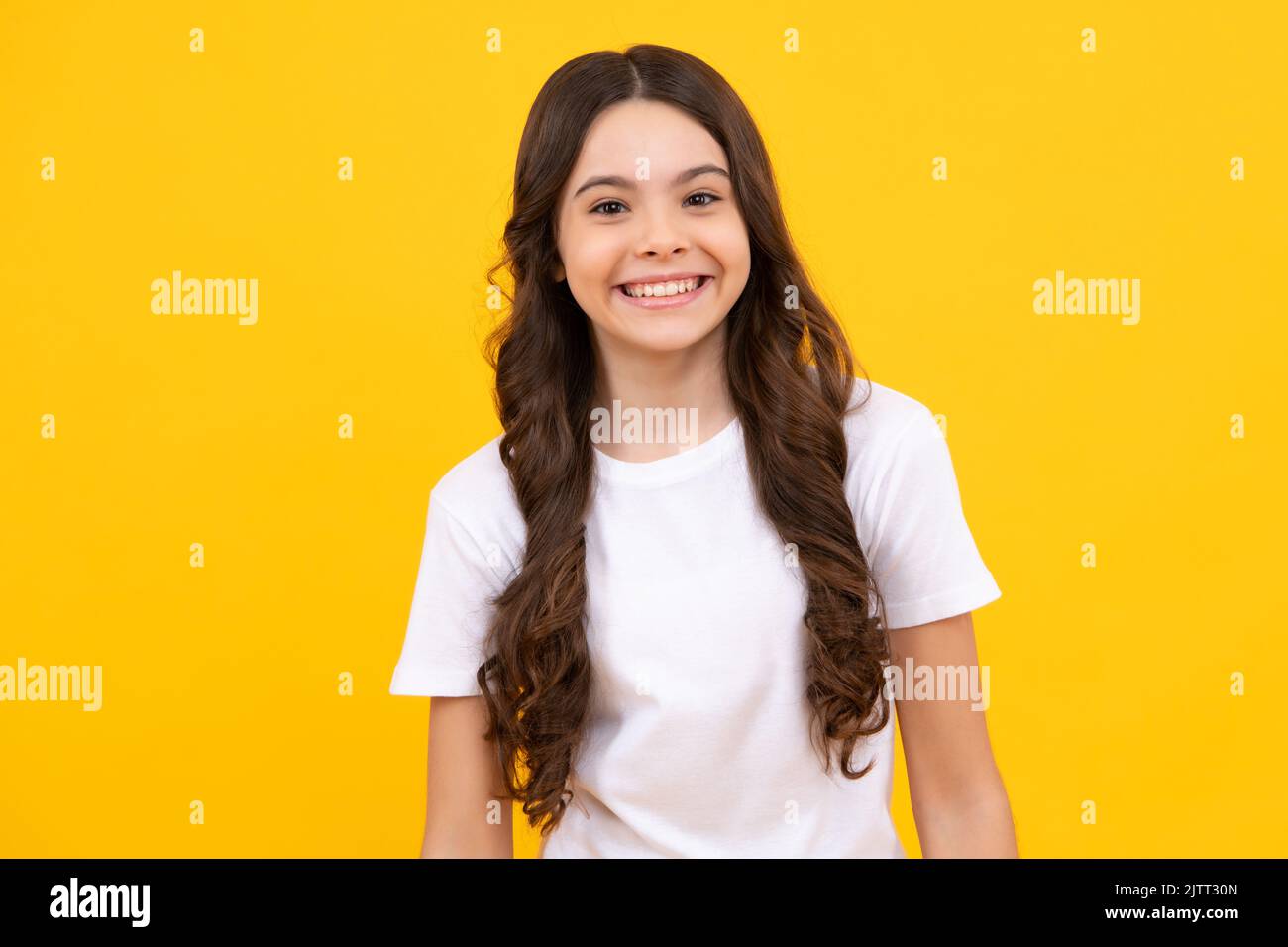 Two young little girls 12-13 years old in white t-shirt blue school uniform  dresses isolated on yellow background children studio portrait Childhood  kids education lifestyle concept Mock up copy space Stock Photo