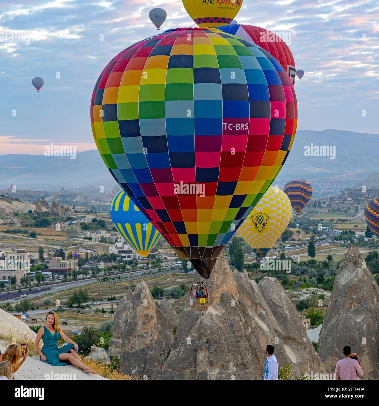 GOREME/TURKEY - June 30, 2022: tourists take pictures with hot air balloons in the background Stock Photo