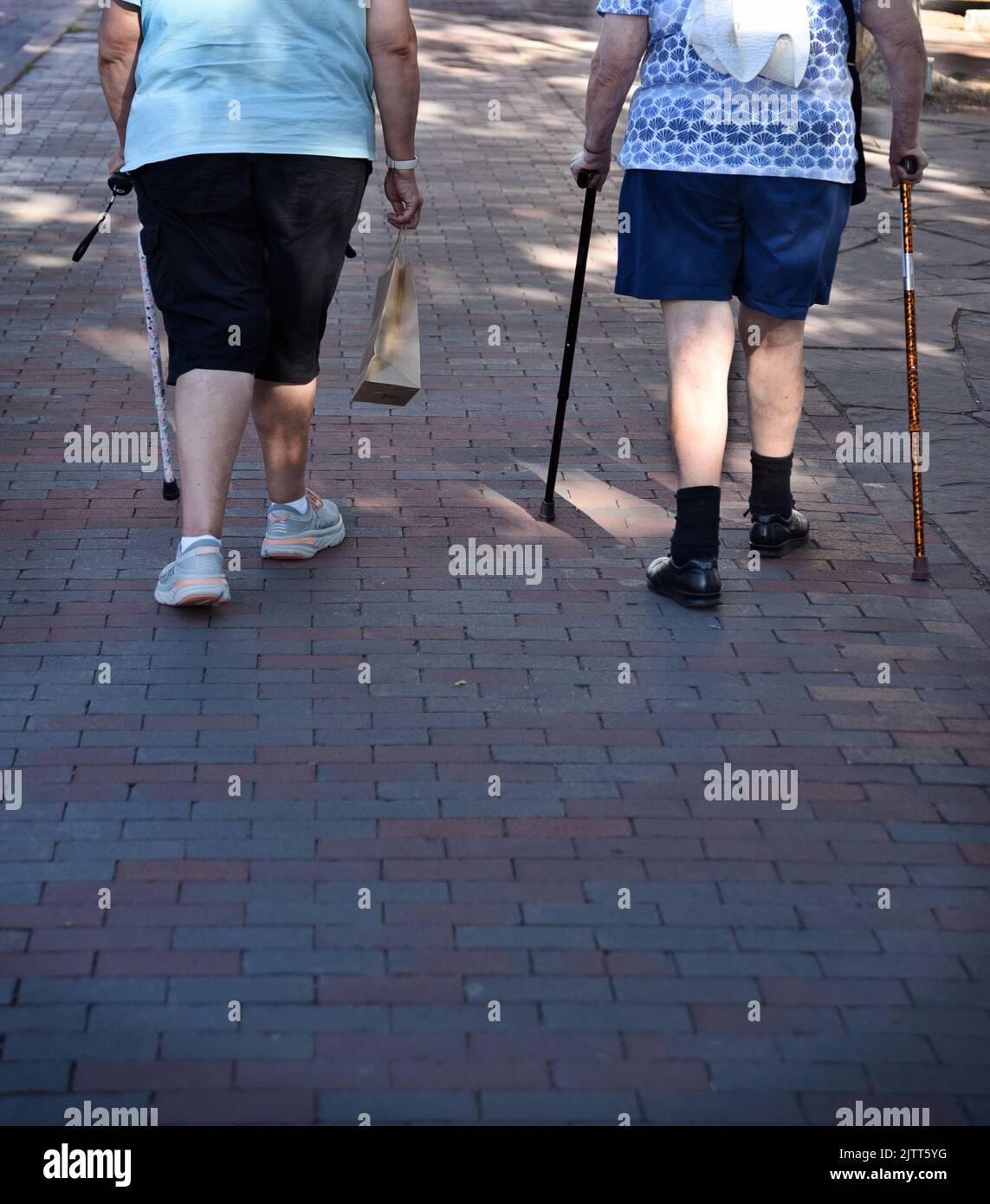 Two elderly women with walking canes walk along a sidewalk in Santa Fe, New Mexico. Stock Photo