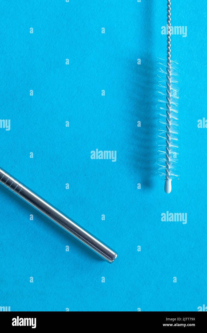 reusable stainless steel straws and cleaning brush on blue background