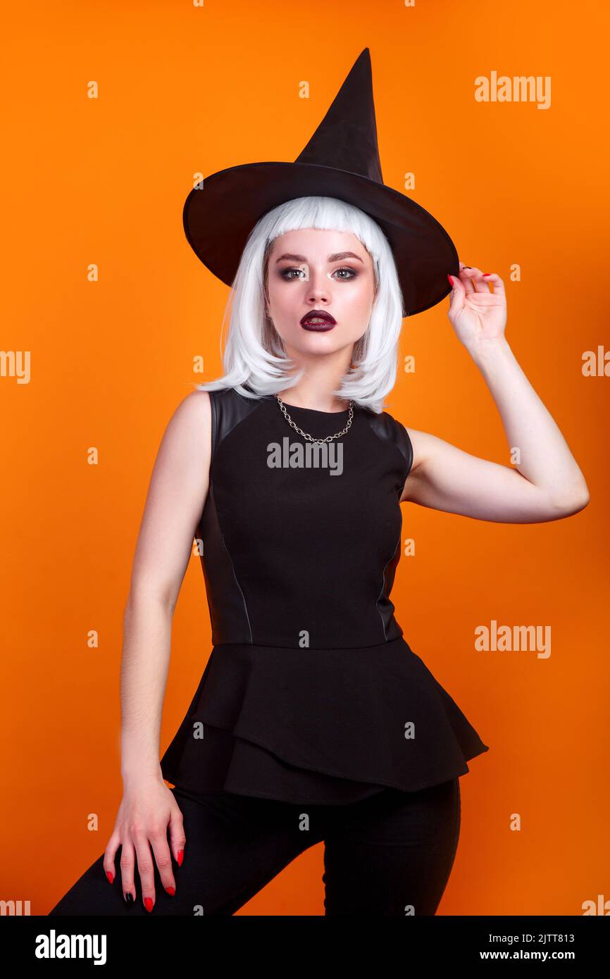 Sexy halloween woman witch on orange background . Stock Photo