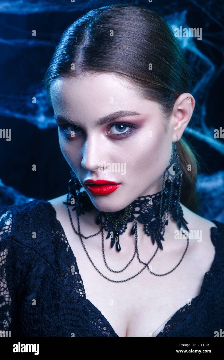 Close-up of beautiful sexy Halloween vampire woman portrait on dark magic background Stock Photo