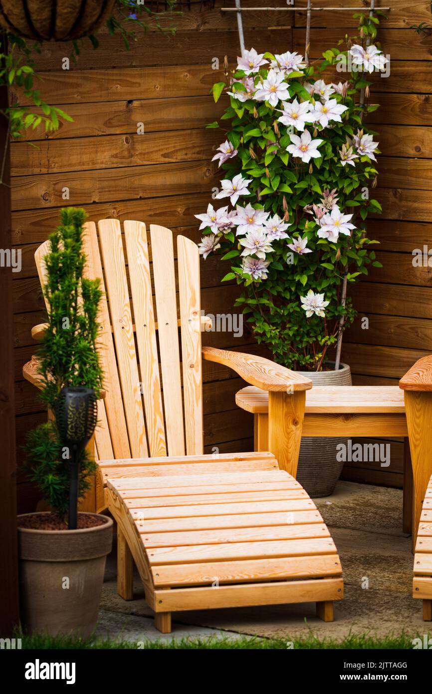 A cozy corner on veranda of wooden house with wooden garden chair, table and white Clematis flowers Stock Photo