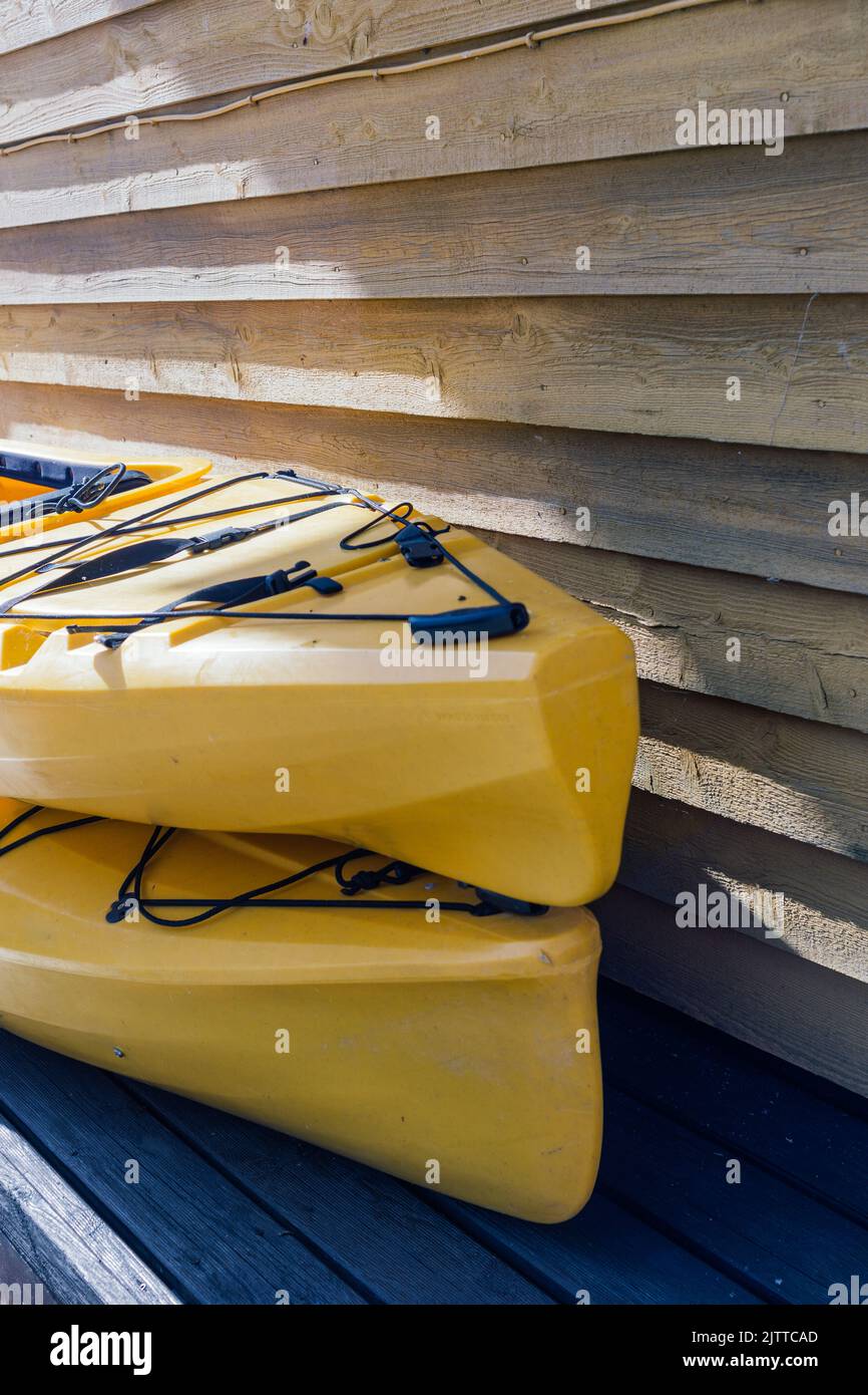 two yellow kayaks stacked next to a wooden wall Stock Photo Alamy