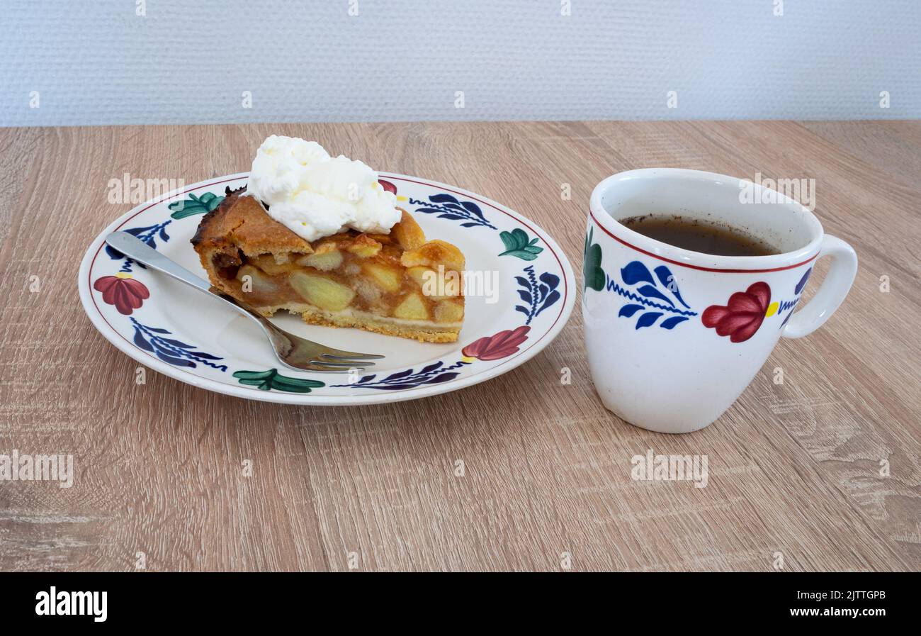 Traditional Dutch apple pie with a cup of coffee. Ceramics are in hand-painted farmer's pattern ('boerenbont') on a wooden table. Stock Photo
