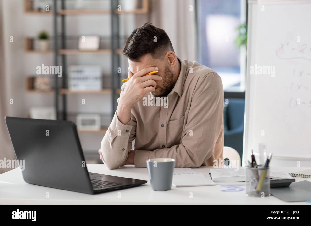 tired male teacher with laptop working at home Stock Photo