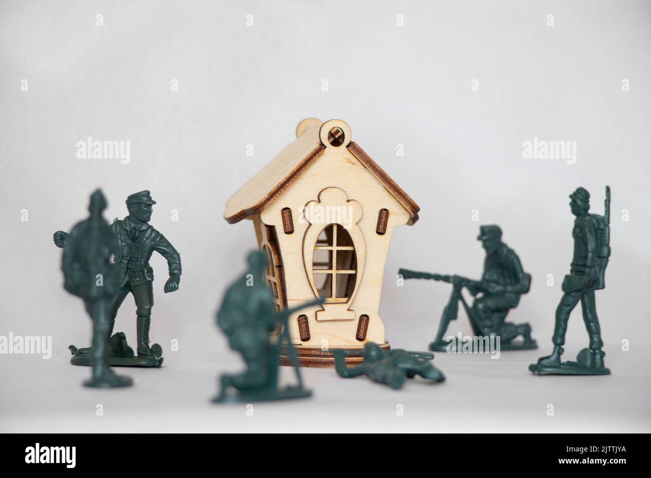 Children's wooden small house and plastic soldiers on a white background, warfare, children's game of war games, army, attack on the house Stock Photo