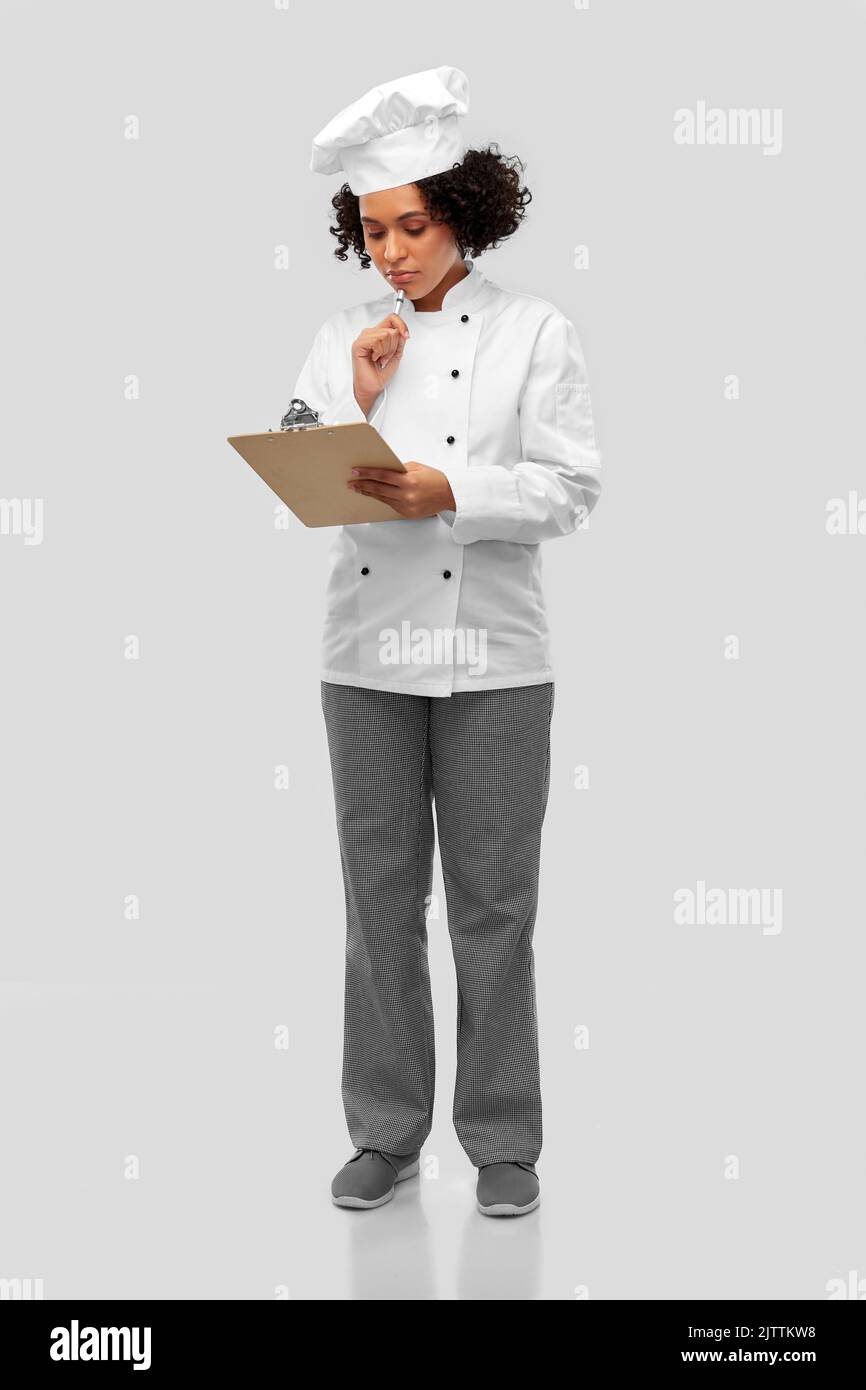 thinking female chef with clipboard and pen Stock Photo
