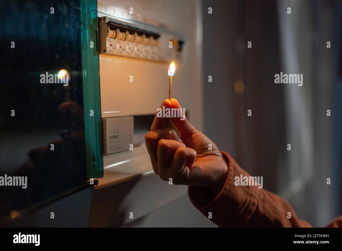 hand with burning matchstick near electric board Stock Photo Alamy