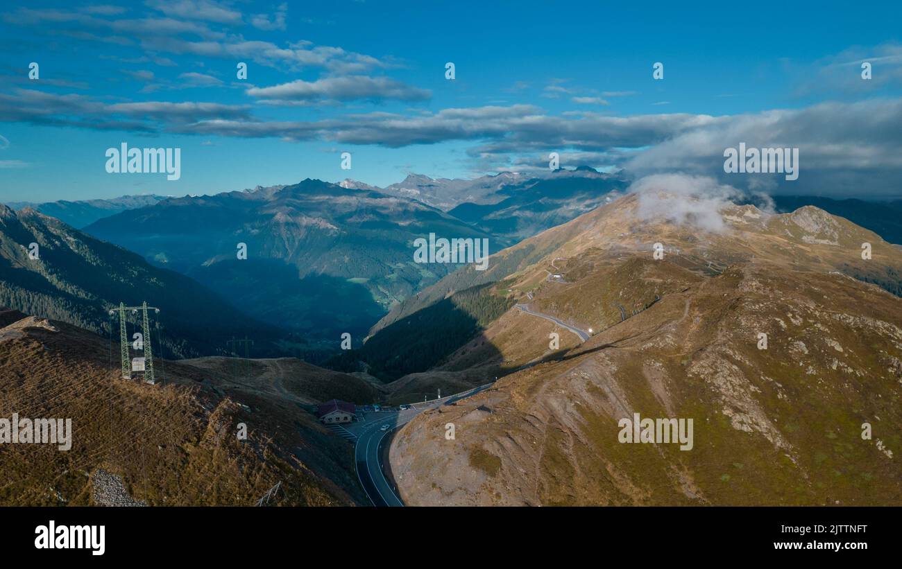 Drone aerial panorama on the Jaufenpass or Passo Giovo in northern italy with beautiful road winding on the mountain and sun just rising over the dolo Stock Photo