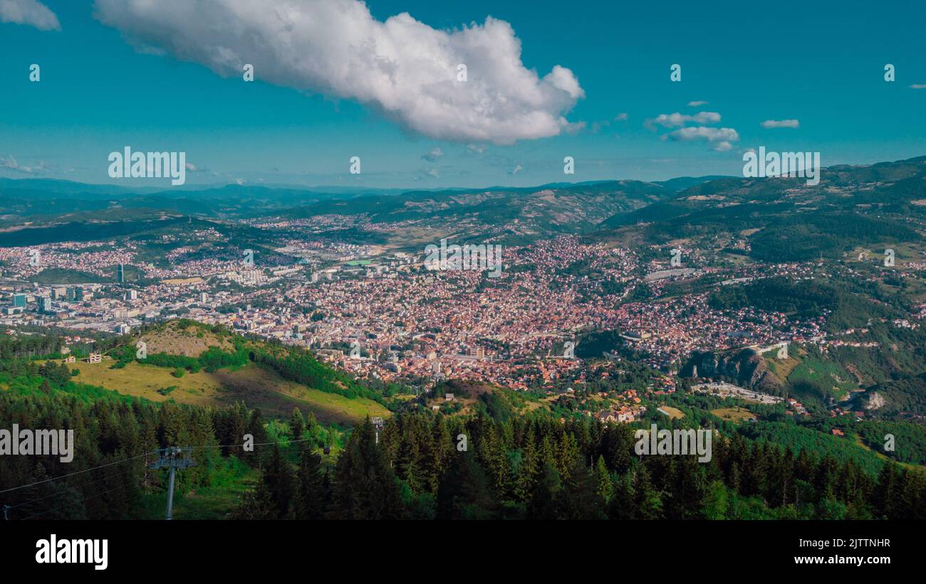 Aerial drone panorama of the city of Sarajevo on a summer day. Viewed from a vantage point close to upper station of gondola or cable car. Stock Photo