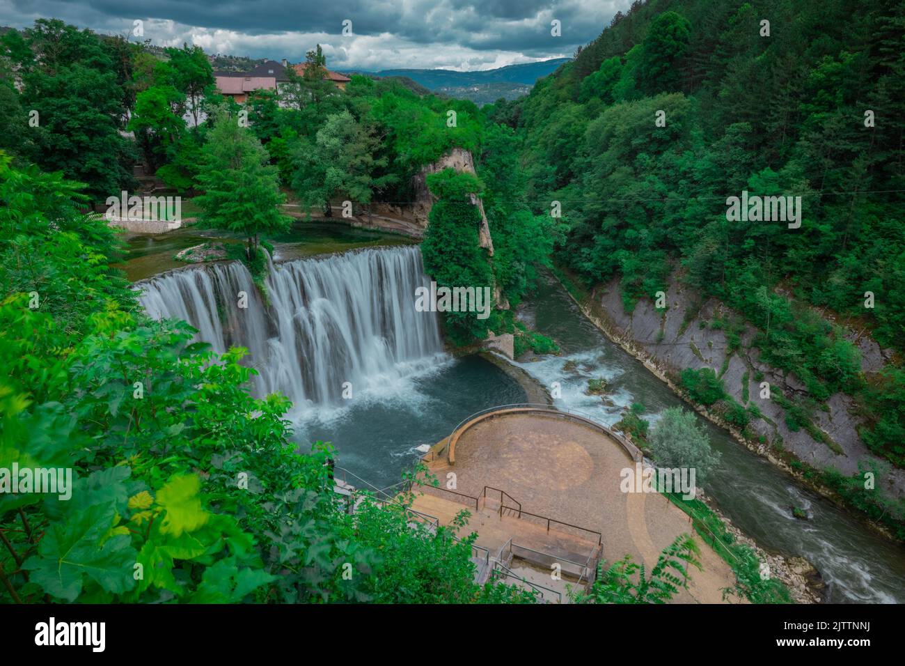 Long exposure panorama of Pliva river waterfalls at Jajce, bosnia and hercegovina. Spectators looking at the waterfalls on a cloudy day. Stock Photo