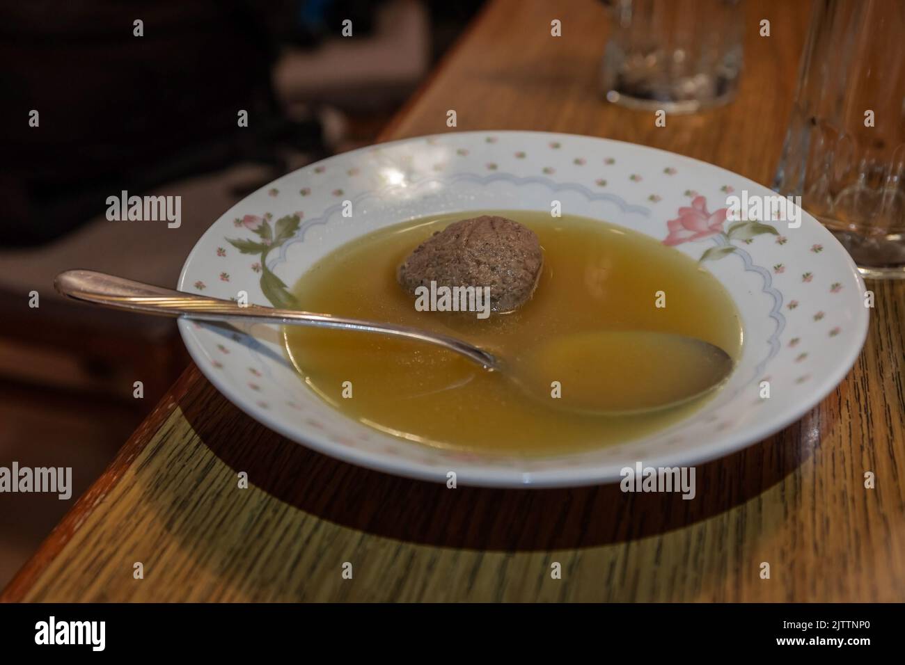 Beef soup with meat ball inside floading in a ceramic bowl or plate resting on a wooden table. Stock Photo