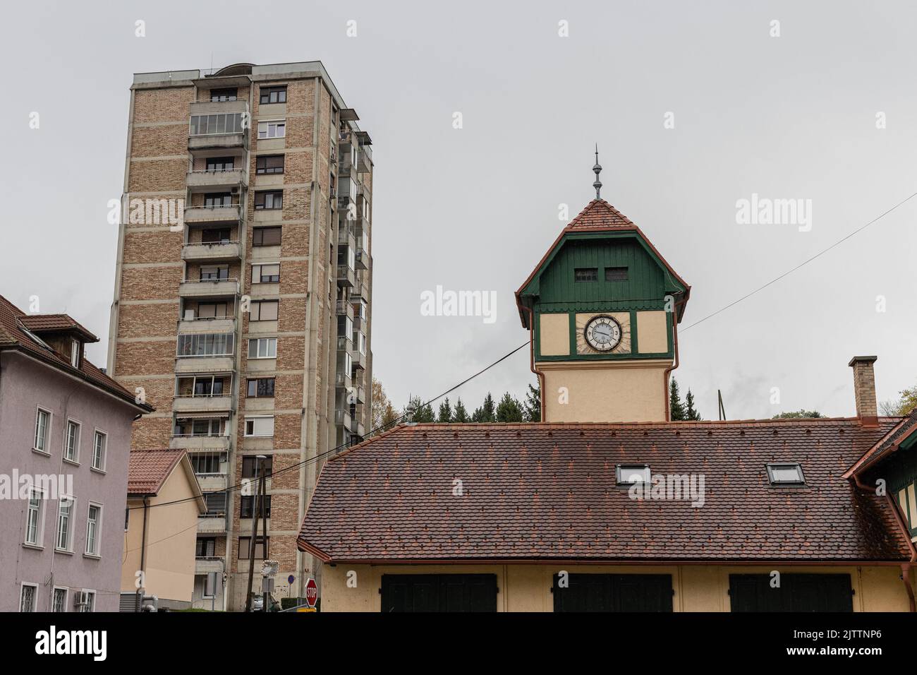 Interesting roof and a small house with clock tower, such as fire station or something similar in trbovlje, slovenia. Old city block in the background Stock Photo